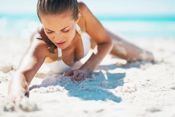 Гламурна молода жінка в купальнику лежить на пляжі — стокове фото