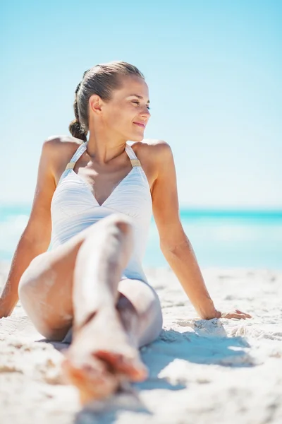 Junge Frau im Badeanzug genießt das Sitzen am Strand — Stockfoto