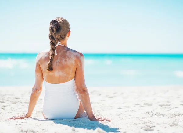 Mujer joven en traje de baño sentado en la playa de arena —  Fotos de Stock