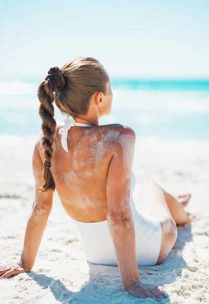 砂浜のビーチの上に座って、日光浴の水着で若い女性 — ストック写真