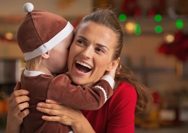 Bebé abrazando feliz madre y en la cocina decorada de Navidad —  Fotos de Stock