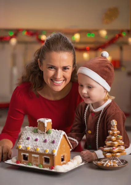Retrato de mãe feliz e bebê fazendo casa de biscoito de Natal — Fotografia de Stock