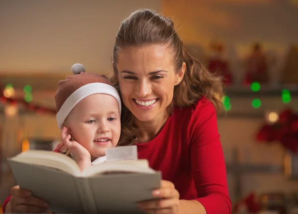 Μητέρα και το μωρό, διαβάζοντας το βιβλίο σε Χριστούγεννα διακόσμηση κουζίνας — Φωτογραφία Αρχείου
