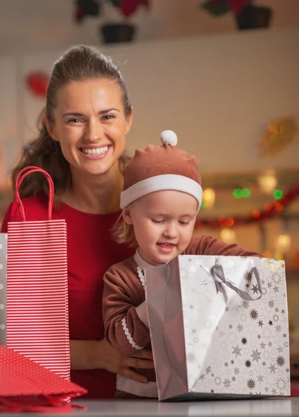 Mãe feliz e bebê verificando sacos de compras de Natal — Fotografia de Stock