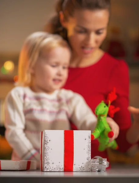 Christmas present box and happy mother and baby in background — Stock Photo, Image