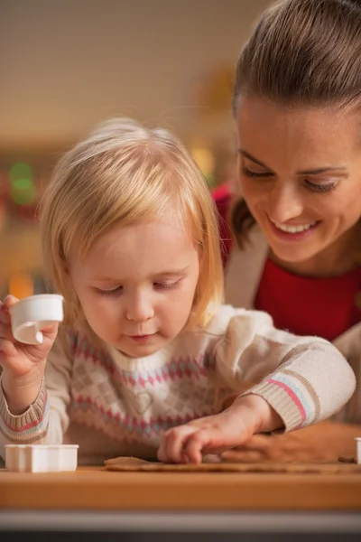 Baby helping other cutting christmas cookies from dough — Stock Photo, Image