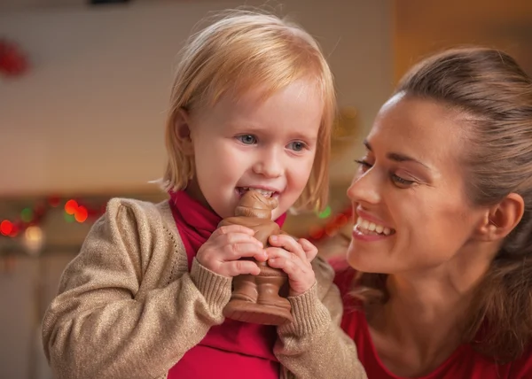 Lycklig mor och barn äta choklad santa — Stockfoto