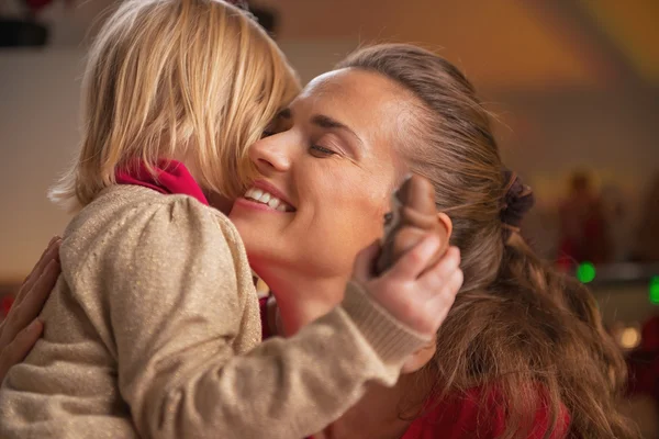 Portrait of baby hugging mother in christmas decorated kitchen — Stock Photo, Image