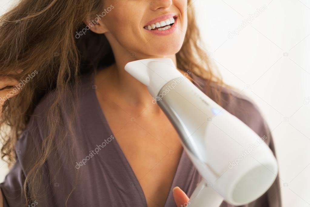 Closeup on happy woman blow drying hair