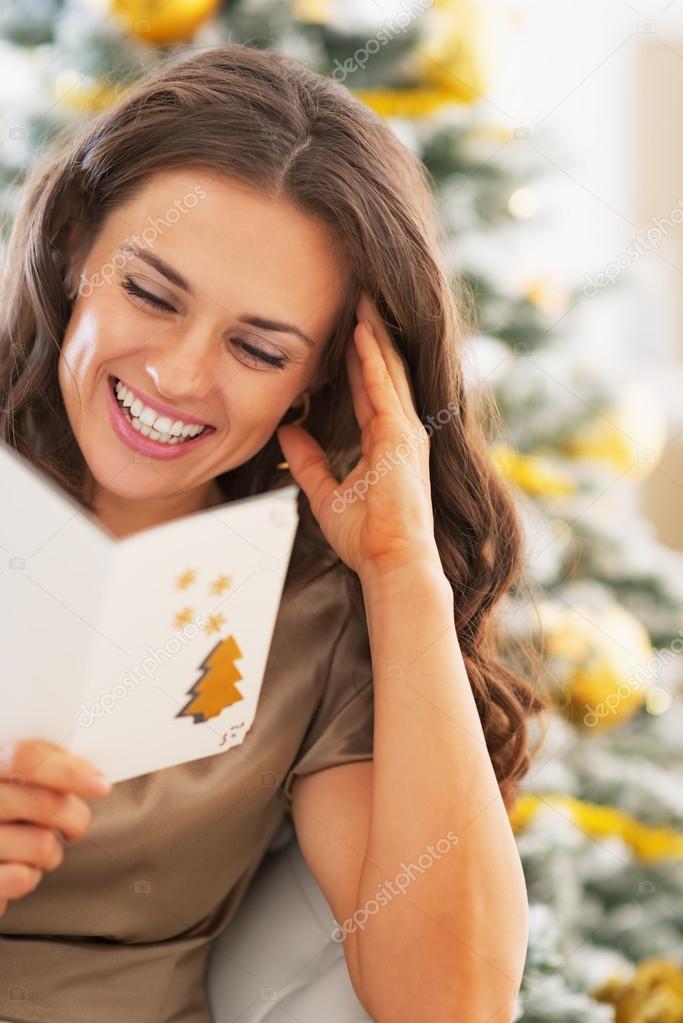 Smiling young woman reading christmas postcard