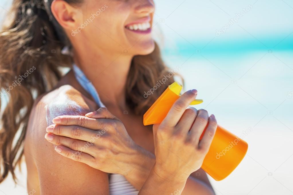 Closeup on smiling young woman applying sun block creme