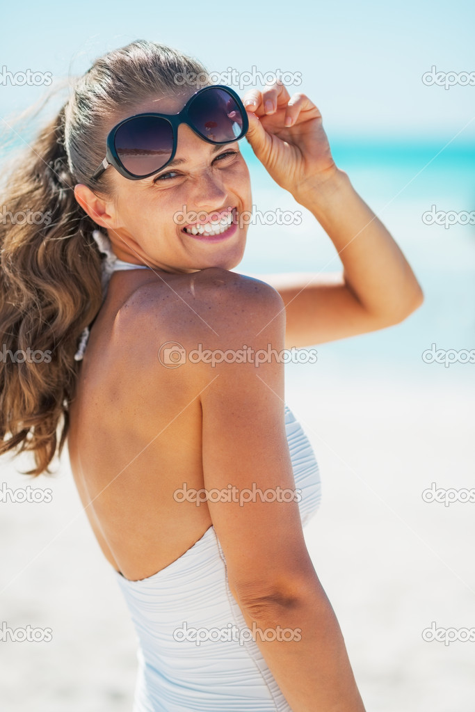 Portrait of smiling young woman in swimsuit with sunglasses