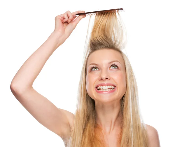 Smiling young woman combing hair — Stock Photo, Image