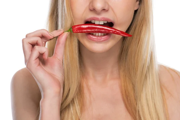 Closeup on young woman with red chili pepper in mouth — Stock Photo, Image