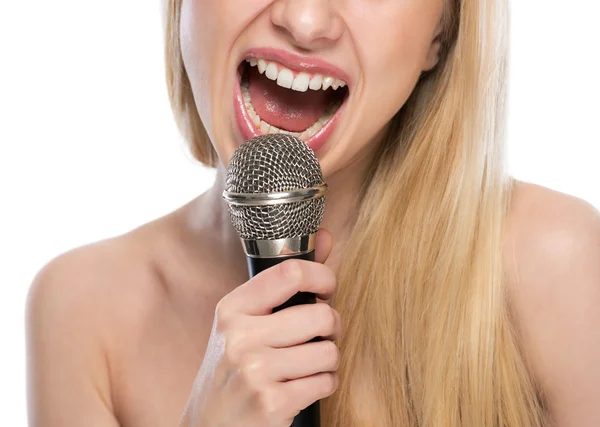 Крупный план молодой женщины, поющей с микрофоном — стоковое фото