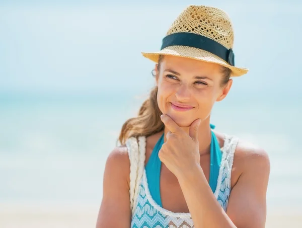 Nachdenkliche junge Frau mit Hut am Strand — Stockfoto