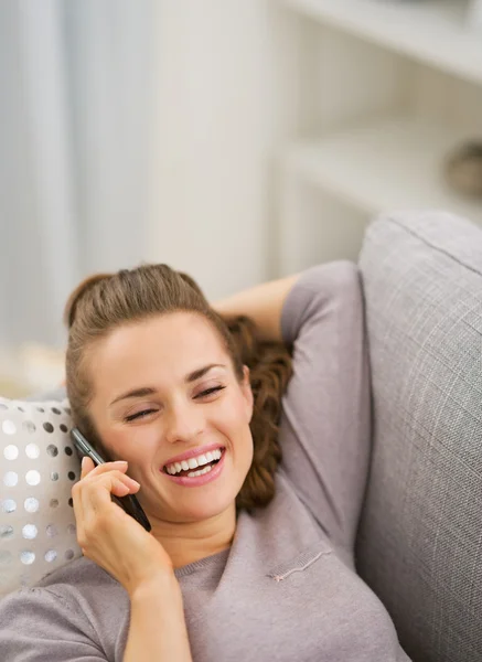 Šťastná mladá žena mluvící mobil zároveň na pohovce — Stock fotografie