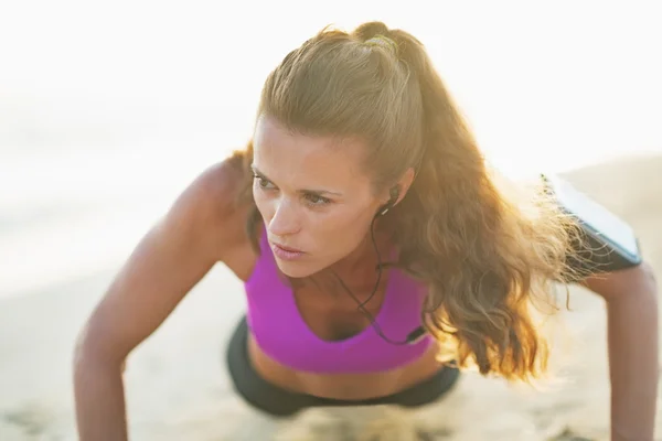 Fitness jeune femme faisant des pompes sur la plage — Photo