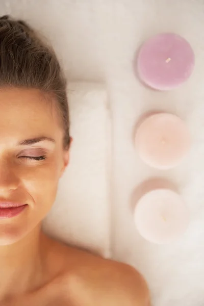 Portrait of young woman laying on massage table near candles — Stock Photo, Image