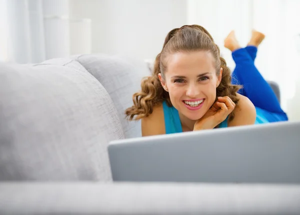 Jonge vrouw sofa opleggen en met behulp van laptop — Stockfoto