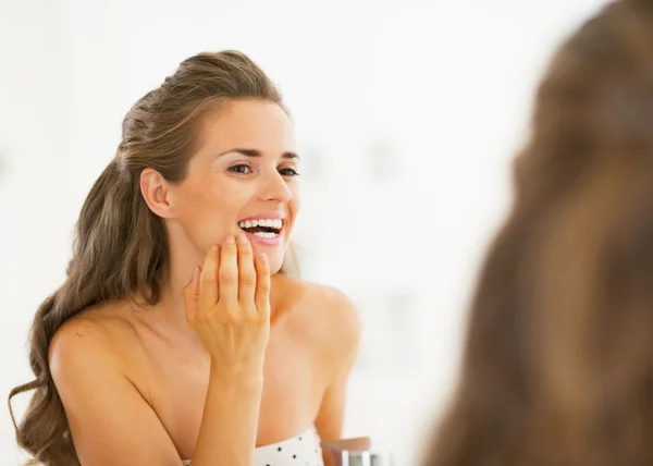 Happy young woman checking teeth in shower teeth in mirror — Stock Photo, Image