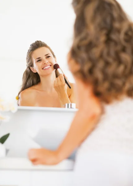 Gelukkig jonge vrouw toepassing van make-up in badkamer — Stockfoto