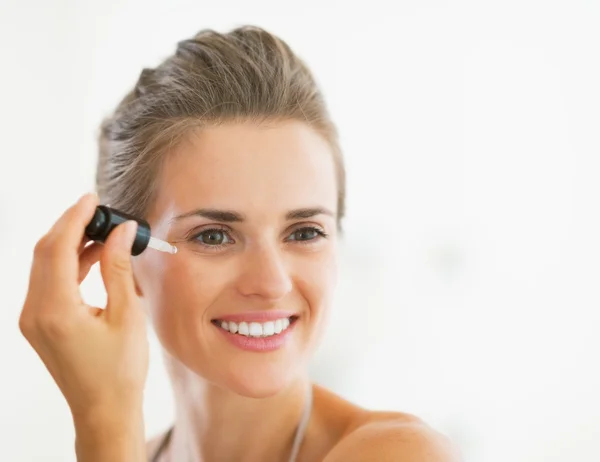 Portrait of happy young woman applying cosmetic serum — Stock Photo, Image