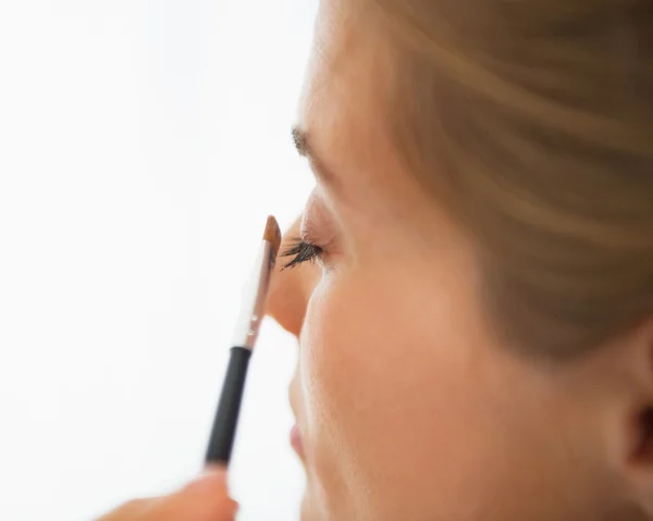 Close-up em jovem mulher aplicando sombras oculares — Fotografia de Stock