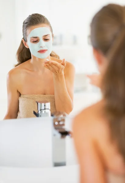 Jovem mulher aplicando máscara facial no banheiro — Fotografia de Stock