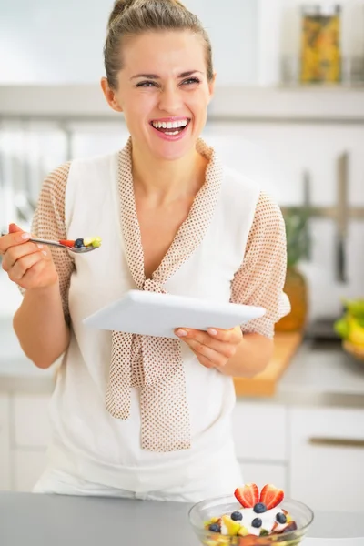 Sorridente giovane donna con tablet pc mangiare macedonia di frutta — Foto Stock