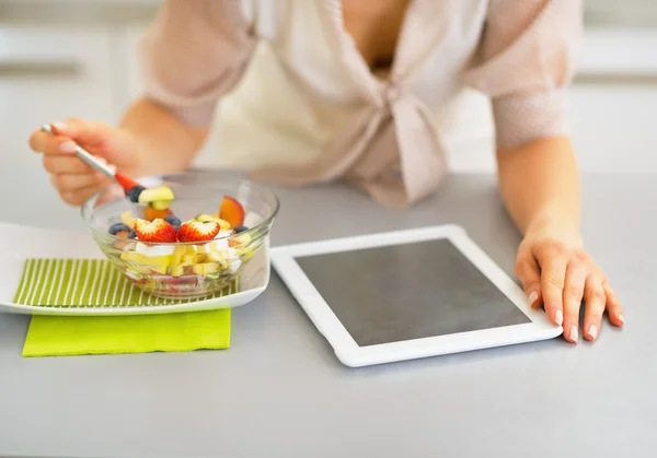 Primer plano de la mujer joven con tableta PC comer ensalada de frutas — Foto de Stock