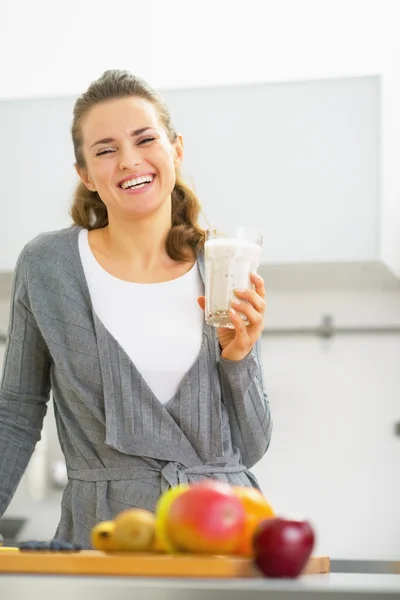 Gelukkig jonge vrouw drinken smoothie in keuken — Stockfoto