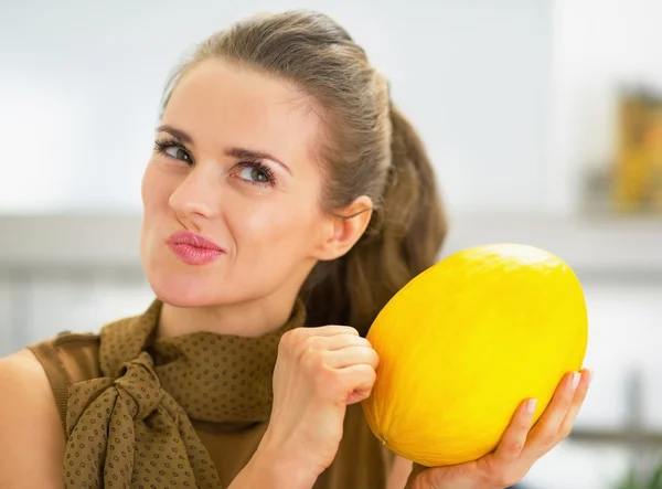 Happy young housewife checking ripeness of melon — Stockfoto