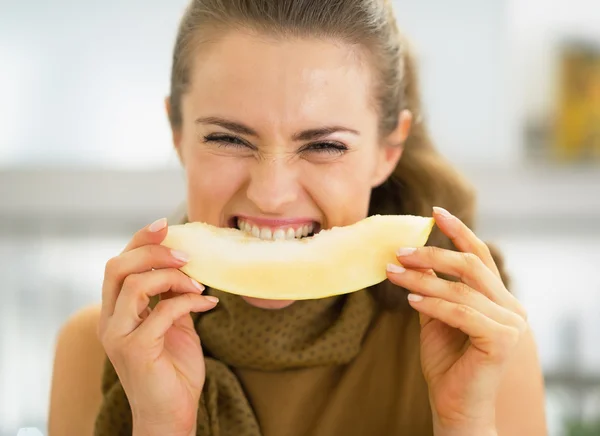 Mujer joven comiendo melón en la cocina —  Fotos de Stock