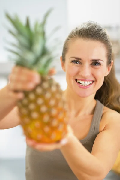 Glückliche junge Frau zeigt Ananas — Stockfoto