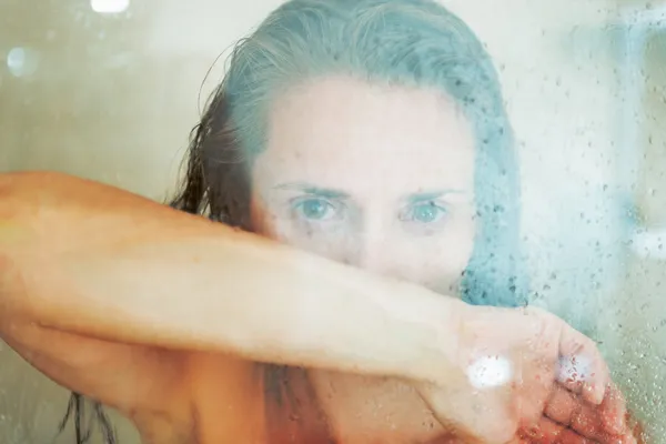 Портрет стурбованої молодої жінки за душовими дверима — стокове фото