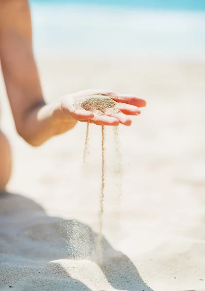 Close-up em jovem mulher sentada na praia e brincando com a areia — Fotografia de Stock