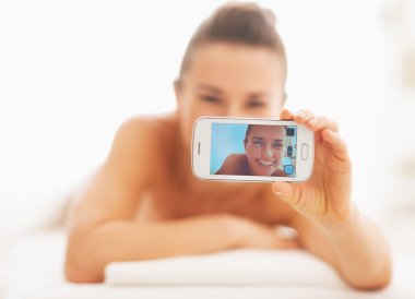 Closeup on young woman taking self photo while laying on massage clipart