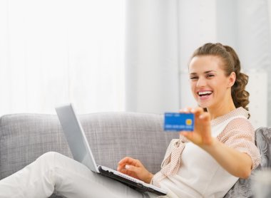 mutlu genç ev hanımı ile kredi kartı gösteren laptop