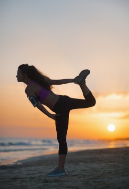 gün batımında sahilde uzanan fitness genç kadın silüeti