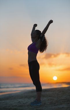 gün batımında sahilde sevindirici fitness genç kadın silüeti