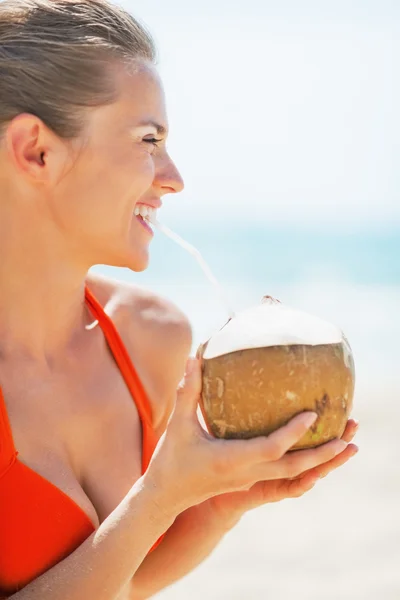Щаслива молода жінка п'є кокосове молоко на пляжі — стокове фото