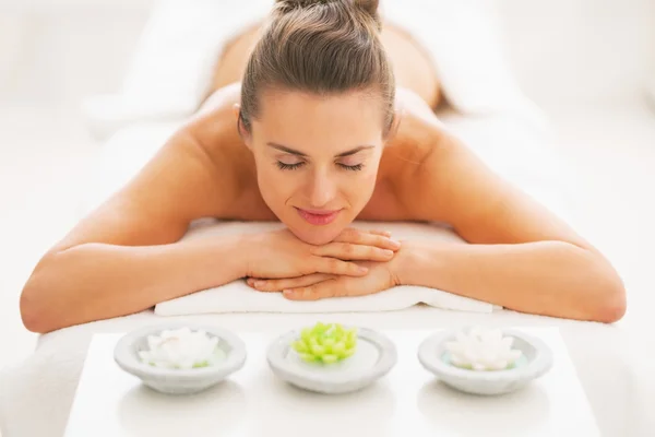 Young woman laying on massage table with candles — Stock Photo, Image