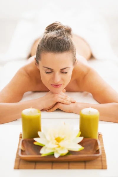 Young woman laying on massage table with candles — Stock Photo, Image