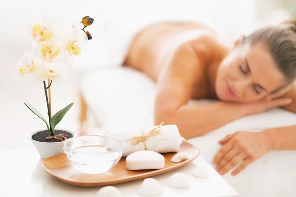 Closeup on spa therapy ingredients and young woman in background — Stock Photo, Image