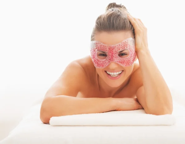 Portrait of smiling young woman in eye mask laying on massage ta — Stock Photo, Image