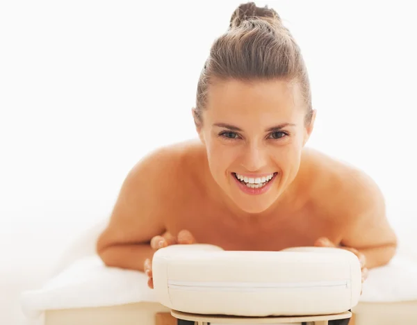 Retrato de mulher jovem sorrindo que põe na mesa de massagem — Fotografia de Stock