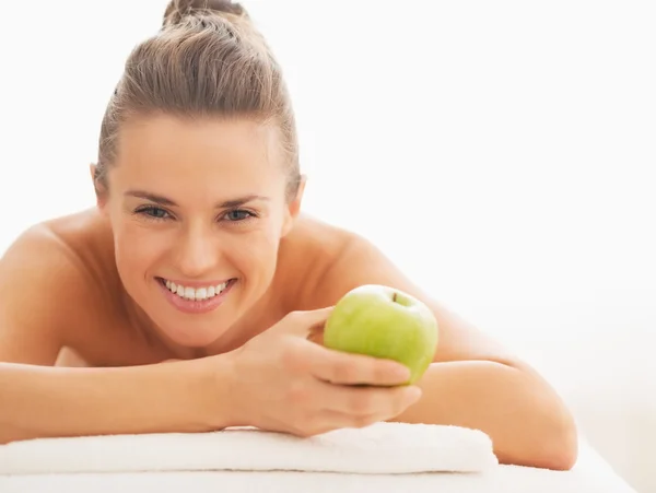 Portret szczęśliwy młoda kobieta z jabłkiem na stół do masażu — Zdjęcie stockowe