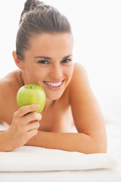 Portret van gelukkige jonge vrouw met apple opleggen massagetafel — Stockfoto