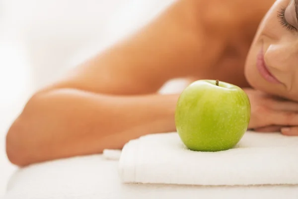 Close-up na jovem mulher relaxada na mesa de massagem com maçã — Fotografia de Stock